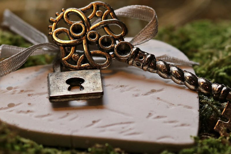 Decorative key and lock on a stone surface with moss in the background