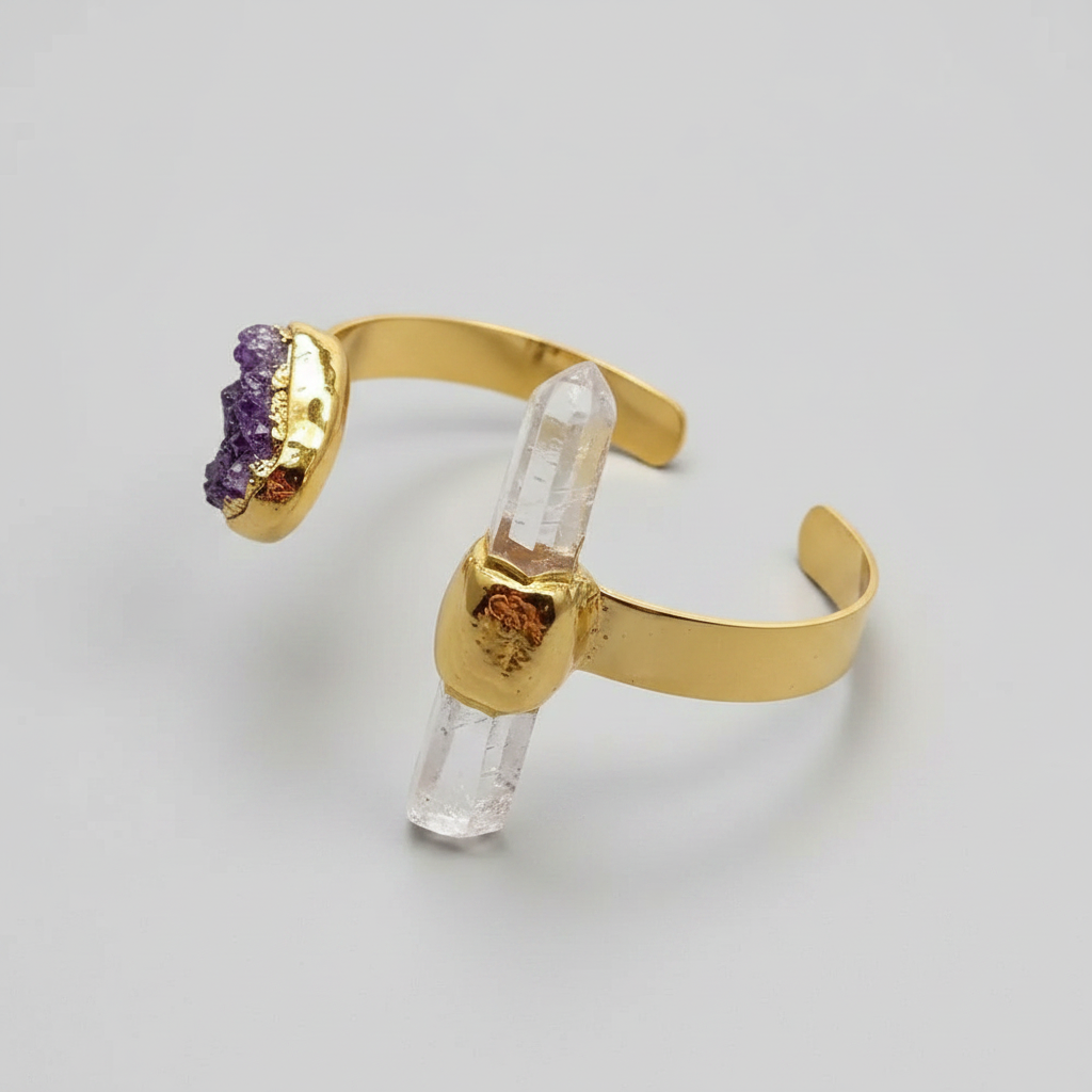 Gold bracelet with raw amethyst and clear quartz crystals on a light gray background