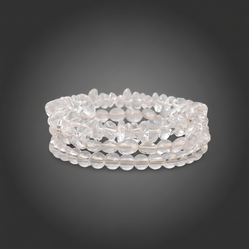 Stack of clear quartz bracelets on a dark gray background