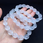 Clear quartz beaded bracelet on a hand with a dark background