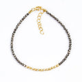 Pyrite nugget bead bracelet with golden metal accents and clasp on white backdrop.