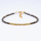 Close up shot of pyrite nugget bead bracelet with golden metal accents on white backdrop.