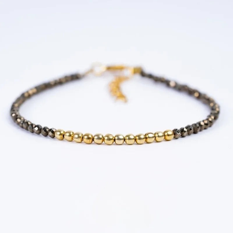Close up shot of pyrite nugget bead bracelet with golden metal accents on white backdrop.